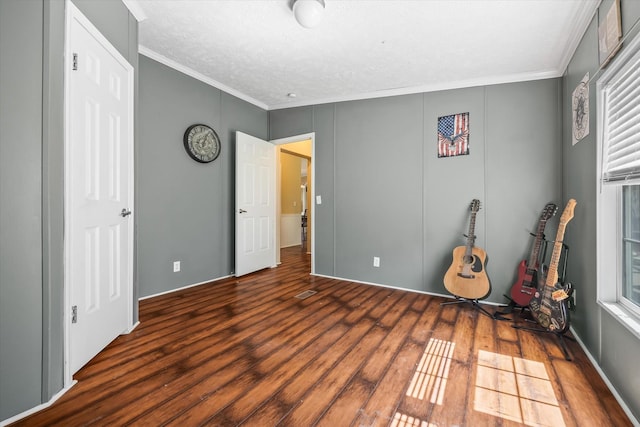 unfurnished bedroom featuring crown molding, dark wood-type flooring, and a textured ceiling