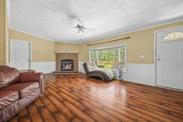 living room with wood-type flooring, a textured ceiling, ceiling fan, and ornamental molding