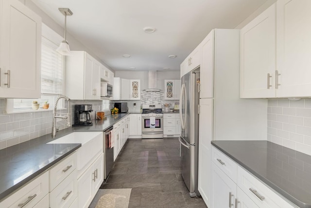 kitchen featuring decorative backsplash, wall chimney exhaust hood, stainless steel appliances, white cabinetry, and hanging light fixtures