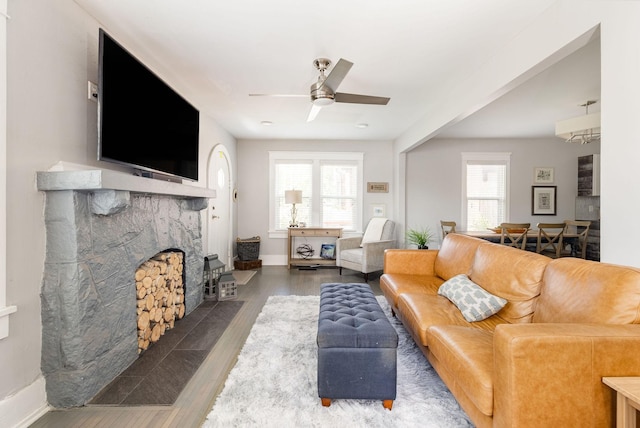 living room with a fireplace, dark hardwood / wood-style floors, ceiling fan, and a healthy amount of sunlight