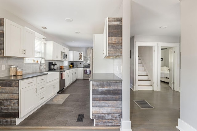 kitchen with tasteful backsplash, white cabinetry, hanging light fixtures, and appliances with stainless steel finishes