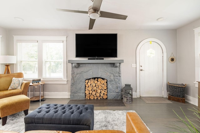 living room with a fireplace, ceiling fan, and dark wood-type flooring