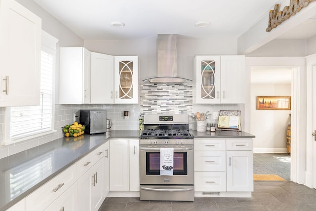 kitchen featuring stainless steel appliances, white cabinetry, tasteful backsplash, and wall chimney range hood