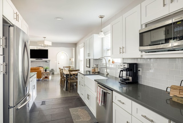 kitchen with white cabinetry, sink, hanging light fixtures, dark hardwood / wood-style floors, and appliances with stainless steel finishes