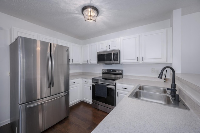 kitchen featuring white cabinets, sink, a textured ceiling, dark hardwood / wood-style flooring, and stainless steel appliances