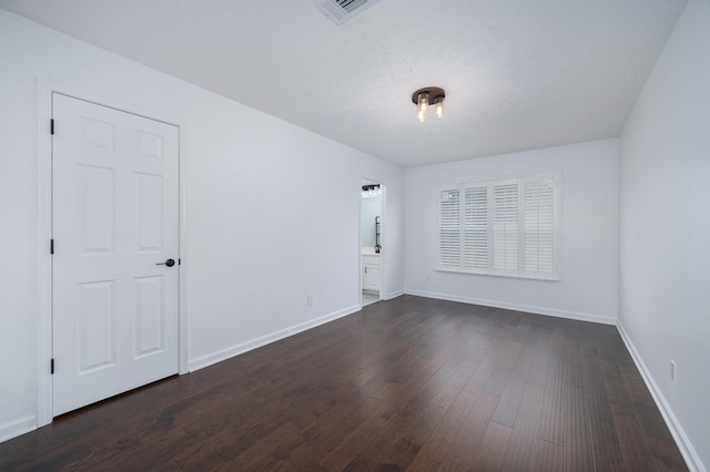 empty room featuring a textured ceiling and dark hardwood / wood-style flooring