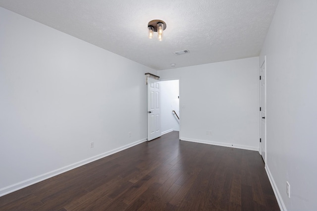 empty room featuring a textured ceiling and dark wood-type flooring