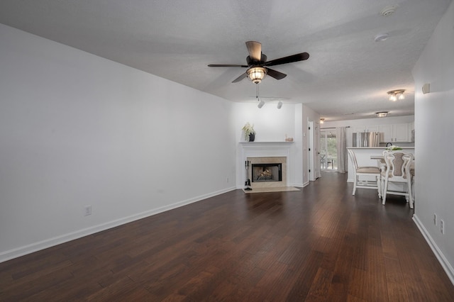 unfurnished living room featuring ceiling fan, dark wood-type flooring, and a textured ceiling