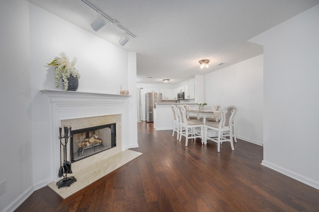 dining area featuring dark hardwood / wood-style floors, a premium fireplace, and rail lighting