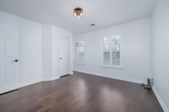 unfurnished room featuring a textured ceiling and dark hardwood / wood-style floors