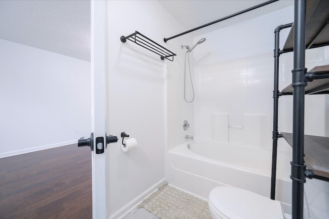 bathroom with hardwood / wood-style floors, shower / bathtub combination, toilet, and a textured ceiling