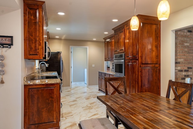 kitchen with light stone countertops, stainless steel appliances, hanging light fixtures, and sink