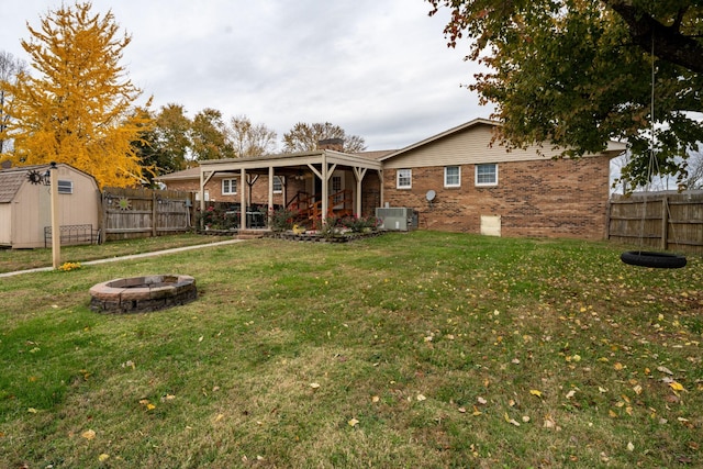 back of house featuring a fire pit, cooling unit, a shed, and a yard