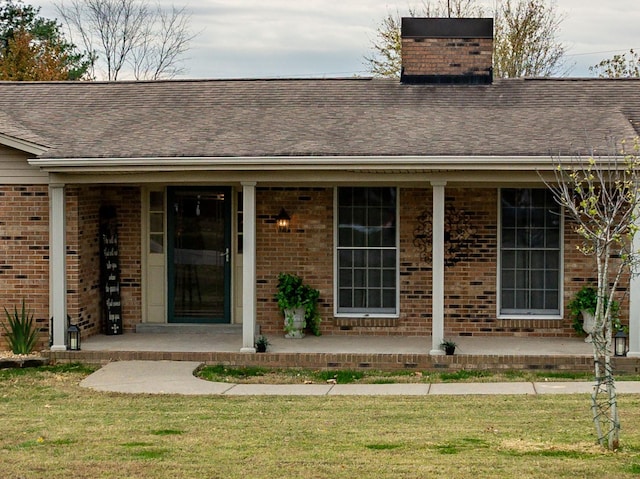 doorway to property with a lawn and a porch