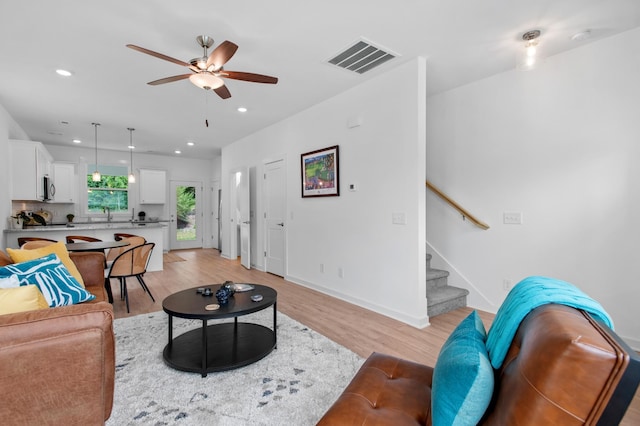 living room featuring ceiling fan, light hardwood / wood-style flooring, and sink