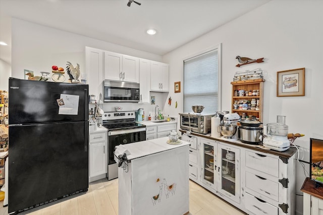 kitchen with a center island, white cabinets, sink, light hardwood / wood-style flooring, and stainless steel appliances