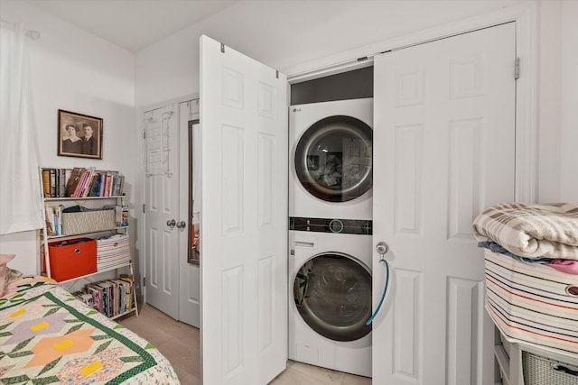 laundry area featuring stacked washer / dryer and light tile patterned floors