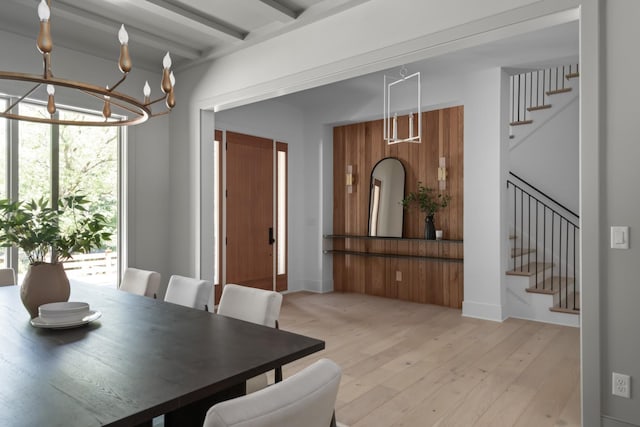 dining space with beamed ceiling, a chandelier, and light wood-type flooring