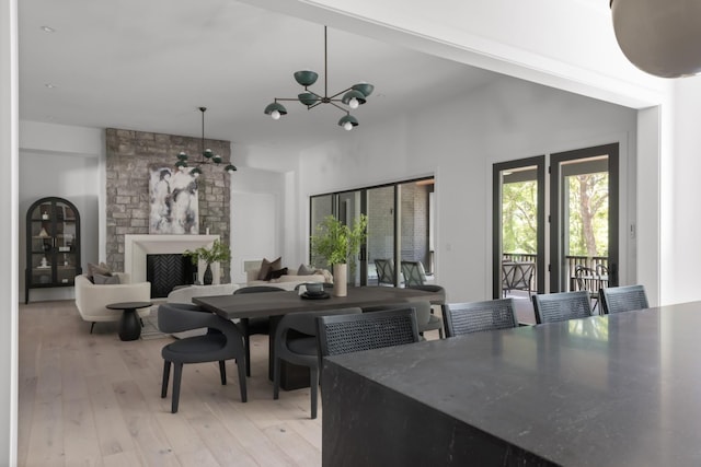 dining space featuring a fireplace, light hardwood / wood-style floors, and an inviting chandelier