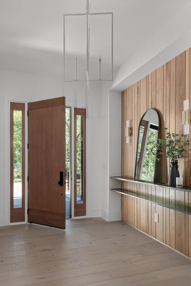 foyer with light hardwood / wood-style floors and wood walls