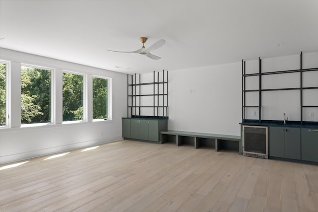 empty room featuring wine cooler, ceiling fan, and light hardwood / wood-style floors