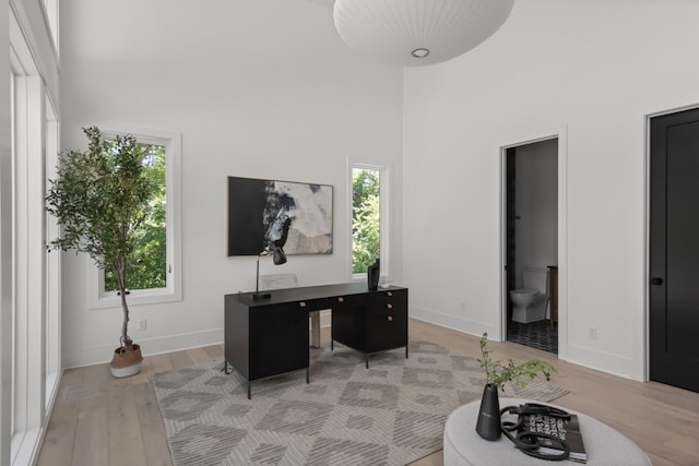 office space with light hardwood / wood-style floors and a high ceiling