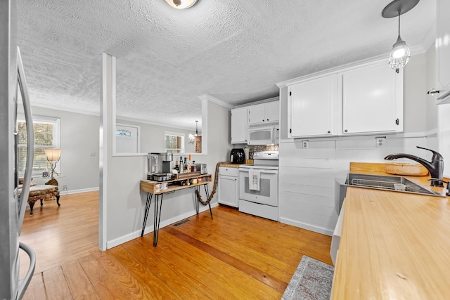 kitchen featuring a wealth of natural light, light hardwood / wood-style flooring, hanging light fixtures, and white appliances