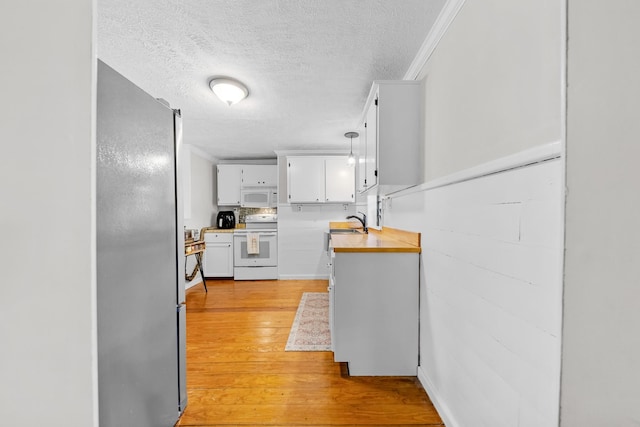 kitchen featuring white appliances, crown molding, sink, light hardwood / wood-style flooring, and white cabinets