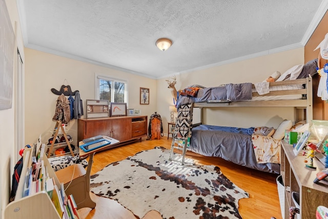 bedroom with crown molding, light hardwood / wood-style flooring, and a textured ceiling