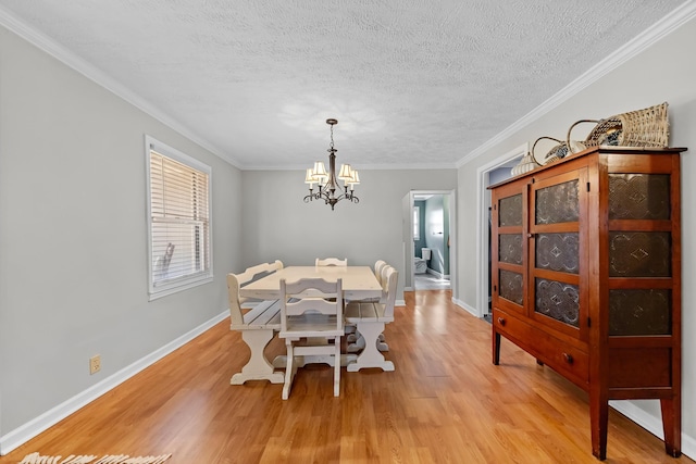 dining room featuring light hardwood / wood-style flooring, ornamental molding, a textured ceiling, and a notable chandelier