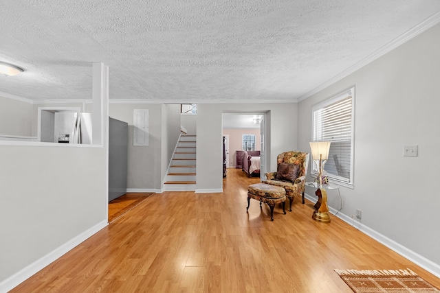 living area with a textured ceiling, light wood-type flooring, and ornamental molding