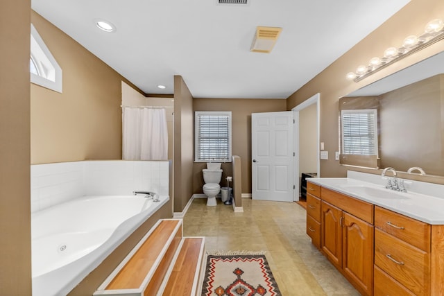 bathroom featuring plenty of natural light, vanity, a bath, and toilet