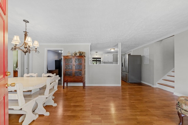 dining room with wood-type flooring, a textured ceiling, an inviting chandelier, and ornamental molding