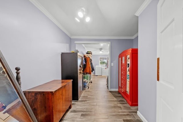 hallway featuring washer and clothes dryer, light wood-type flooring, and ornamental molding