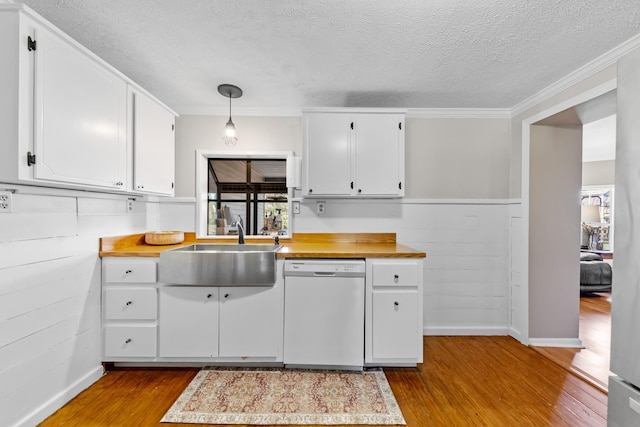 kitchen featuring white dishwasher, crown molding, decorative light fixtures, light hardwood / wood-style floors, and white cabinetry