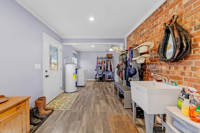 interior space with water heater, light hardwood / wood-style flooring, brick wall, washer / dryer, and ornamental molding