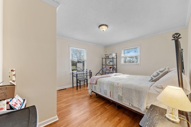 bedroom featuring multiple windows, hardwood / wood-style floors, and ornamental molding