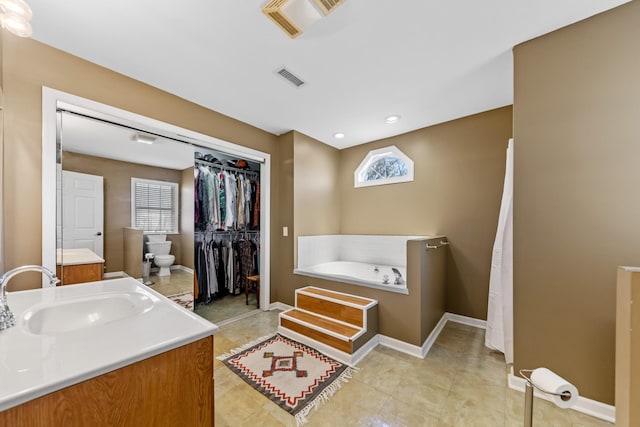 bathroom featuring plenty of natural light, toilet, a tub to relax in, and vanity