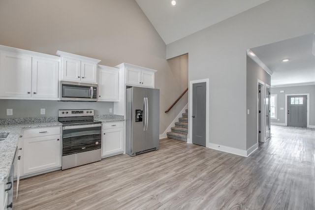 kitchen with light stone countertops, white cabinetry, light wood-type flooring, and appliances with stainless steel finishes