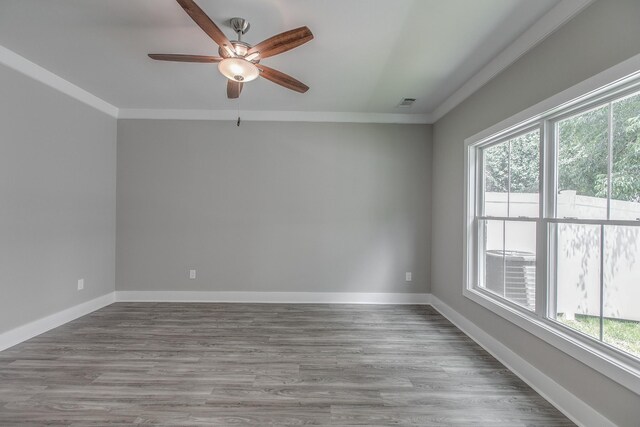 spare room featuring wood-type flooring, a wealth of natural light, and crown molding