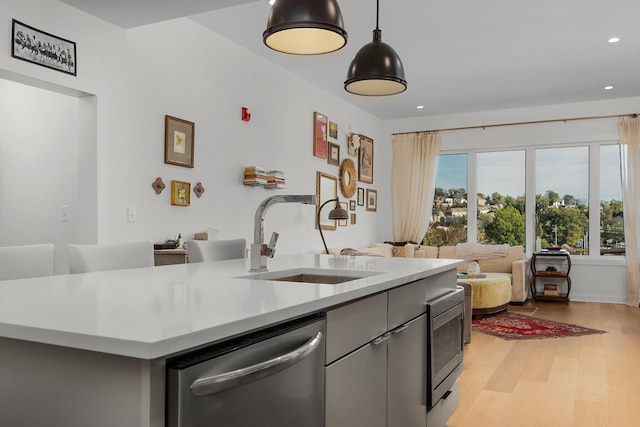 kitchen featuring decorative light fixtures, sink, appliances with stainless steel finishes, and light hardwood / wood-style flooring