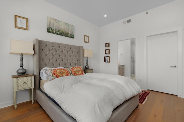 bedroom featuring connected bathroom and hardwood / wood-style floors