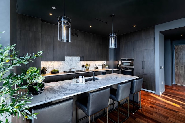 kitchen with a kitchen breakfast bar, decorative light fixtures, and dark wood-type flooring