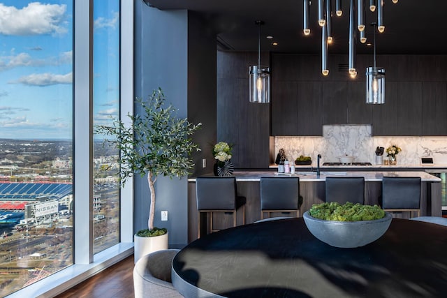 kitchen with dark brown cabinets, tasteful backsplash, hanging light fixtures, and dark wood-type flooring