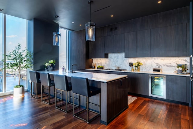 kitchen featuring dark hardwood / wood-style flooring, hanging light fixtures, beverage cooler, and tasteful backsplash