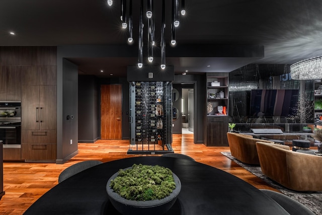 interior space with light wood-type flooring, double oven, and a notable chandelier