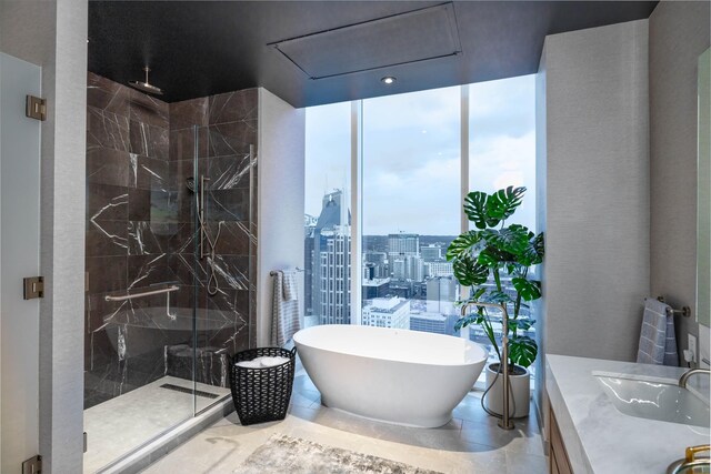 bathroom with tile patterned floors, vanity, and shower with separate bathtub