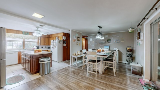 kitchen with ceiling fan, decorative light fixtures, white appliances, a kitchen island, and light wood-type flooring