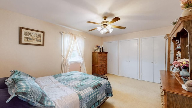 carpeted bedroom with two closets and ceiling fan