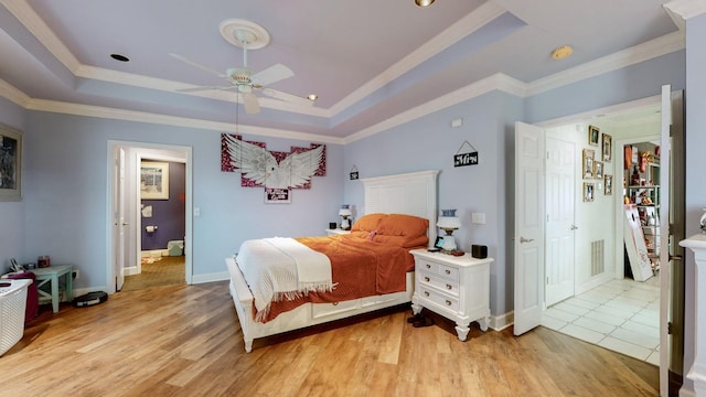 bedroom featuring ceiling fan, a raised ceiling, crown molding, and light hardwood / wood-style flooring